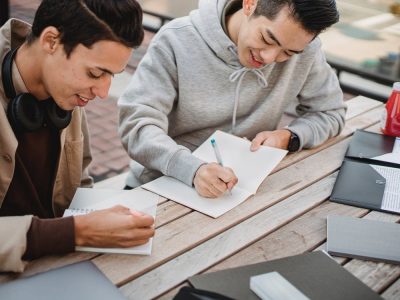 Man in Gray Hoodie Writing on White Paper