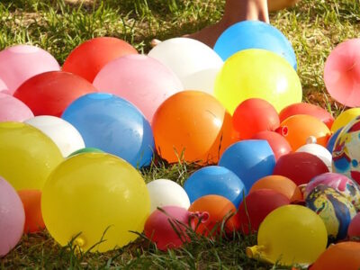 Many colorful balloons scattered on grass