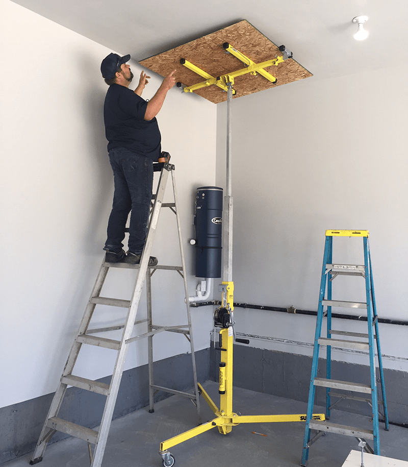 A man installing ceiling in a room.