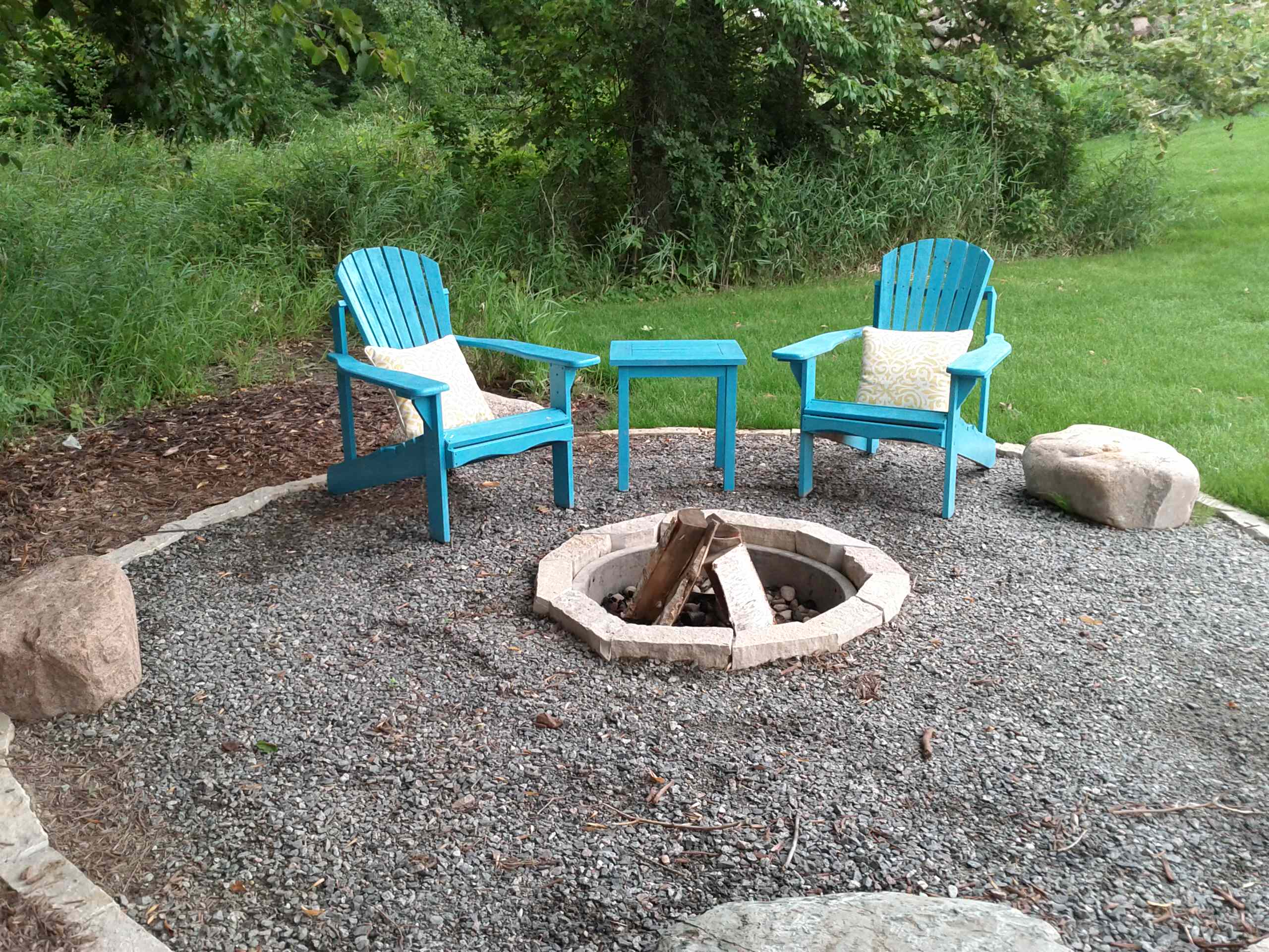 Outdoor fire pit with two blue chairs and a table