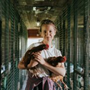 A girl holding two chickens in a cage