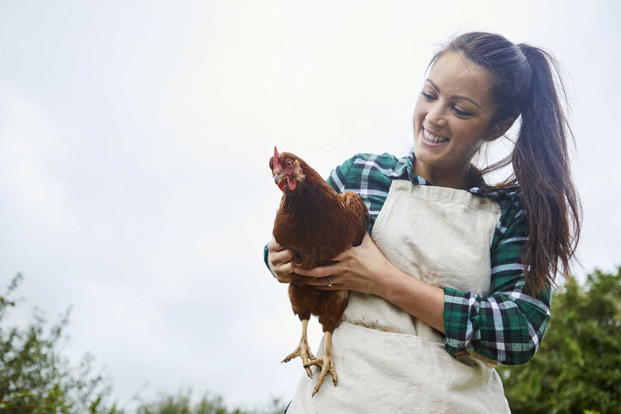 A woman lovingly cradles a chicken in her arms