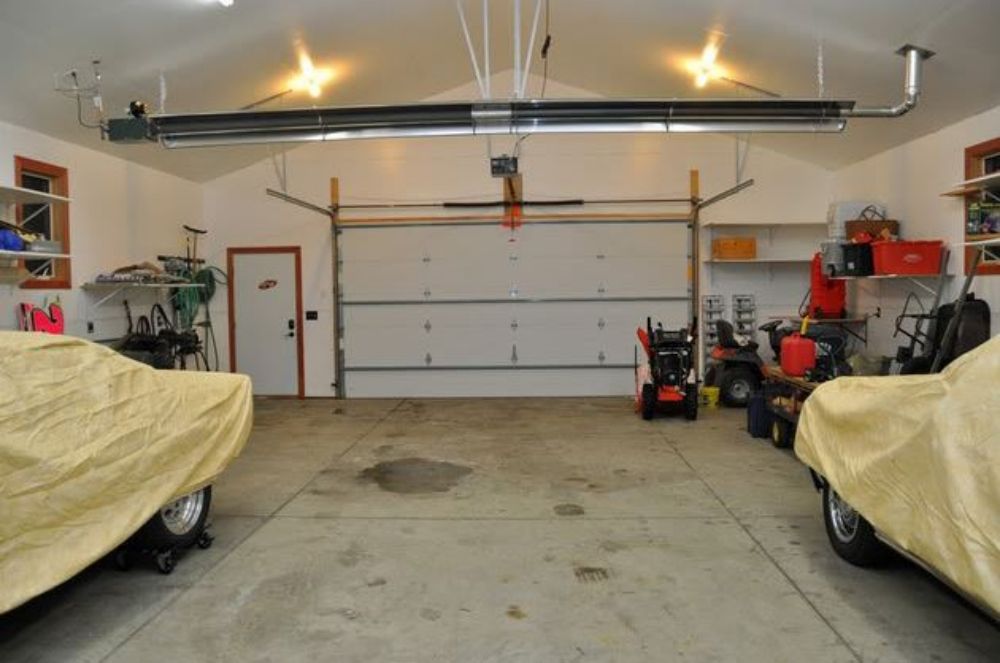 Two cars parked in a garage with a cover