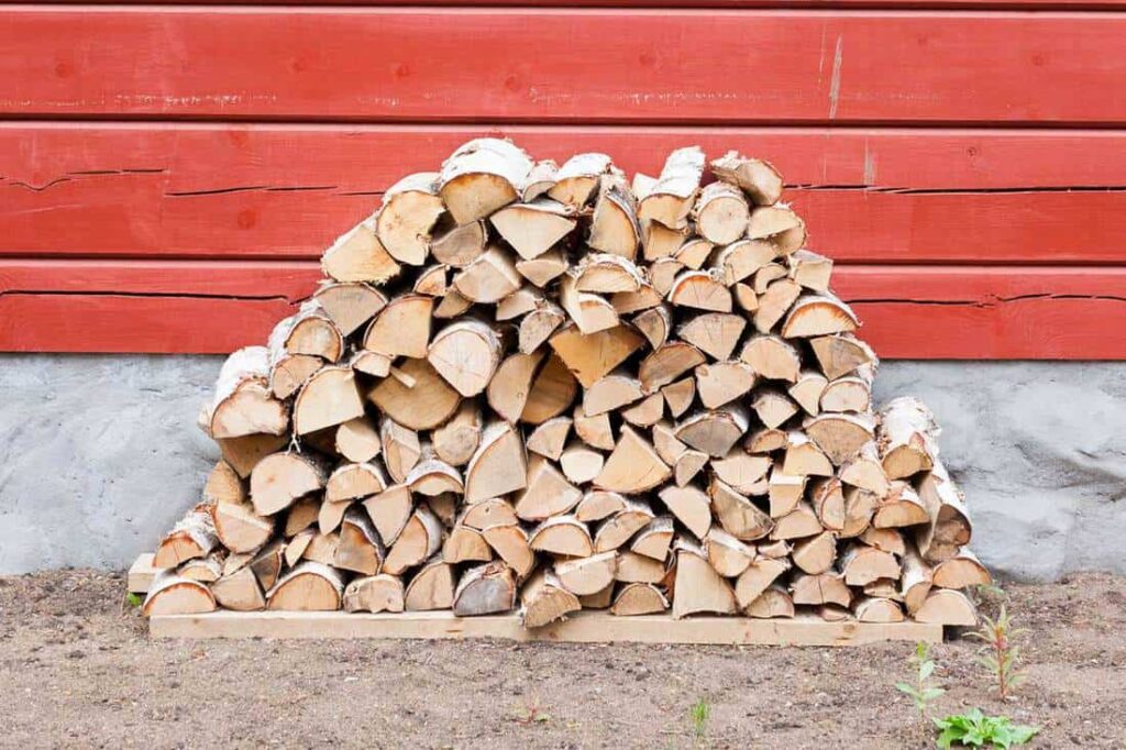 Signs of well-stacked firewood against a red wall