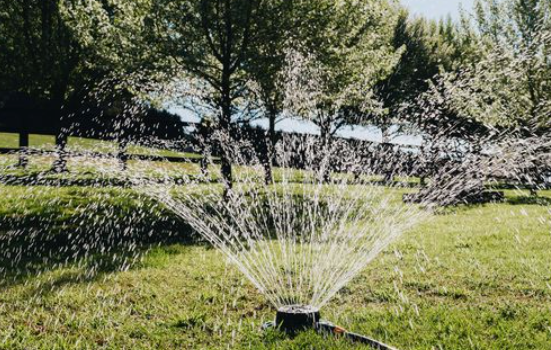A stationary sprinkler spraying water on a grassy field