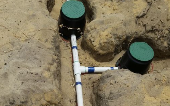 Two pipes connected to a rock wall in a trench