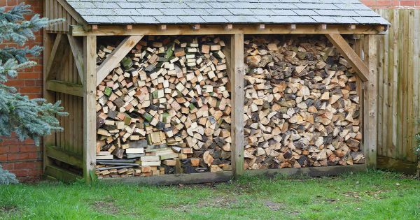 A firewood shed with neatly stacked logs on the outside