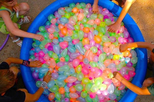 Children joyfully playing in a pool filled with vibrant balloons