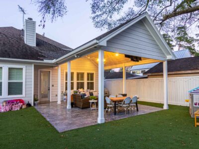 A backyard with a covered patio and a roofed outdoor seating area