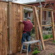 A man diligently constructing a wooden fence, showcasing his craftsmanship and dedication