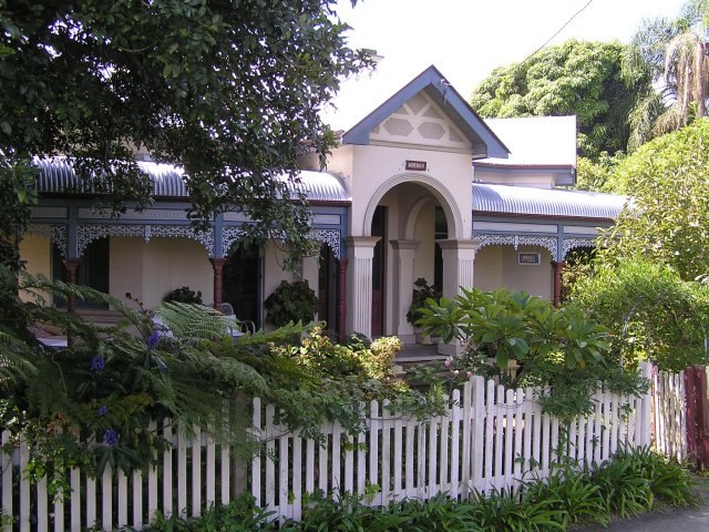 A charming house with a white picket fence and a tree in front, highlighting the importance of a front garden fence