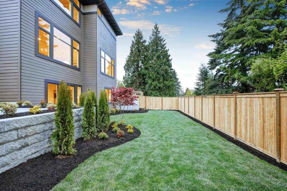 A backyard with a wooden fence and grass, enhancing property value