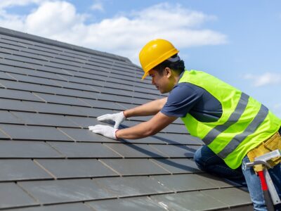 Roof repair, worker with white gloves replacing gray tiles or sh